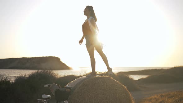 Slim Happy Woman Imitating Flying Bird Standing on Yellow Pile of Wheat in Sunbeam