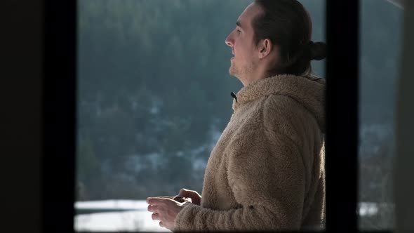 Man drinking tea on balcony.