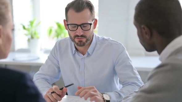 Businessman Explaining Documents to Colleagues