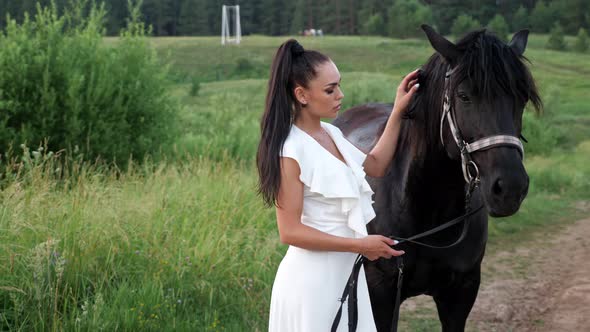 Young Woman Brunette with Hair in Ponytail Pets Black Horse