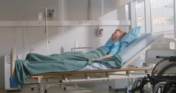 Sad and Weak Sick Boy Lying Alone in Hospital Bed