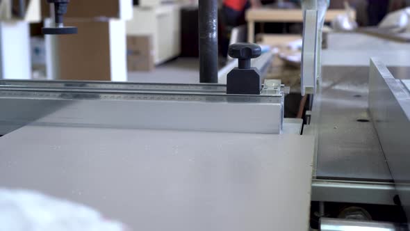 A Man Is Sawing Wooden Parts with a Circular Saw in a Furniture Manufacturing Facility