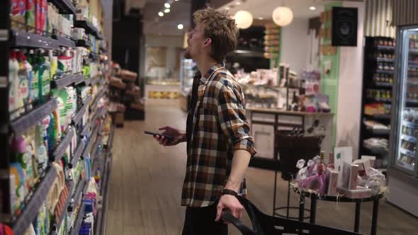 Young Man Using Smartphone in Supermarket