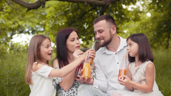 Portrait of Caucasian Parents with Two Cute Daughters Drinking Juice in Glass