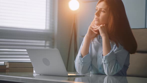 Thoughtful lady nurse in blue medical coat holds head on hands sitting at grey table