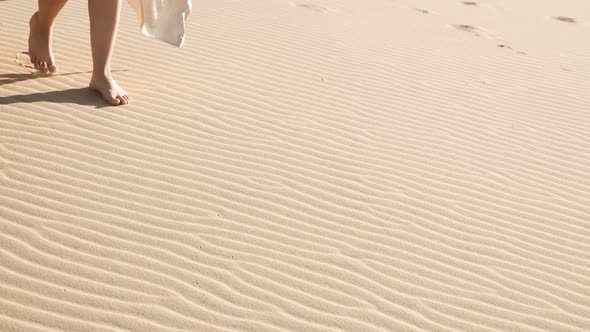 Woman Walking Barefoot Over Rippled Sandy Beach