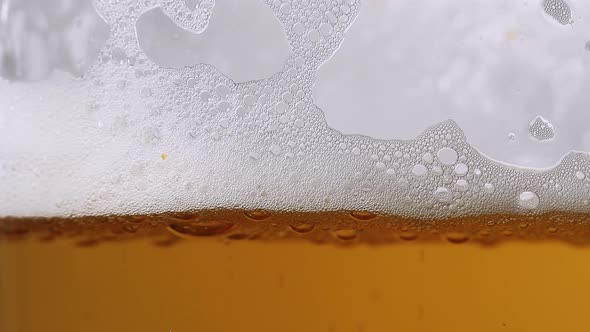 Beer pouring into glass and bubbles are forming foam