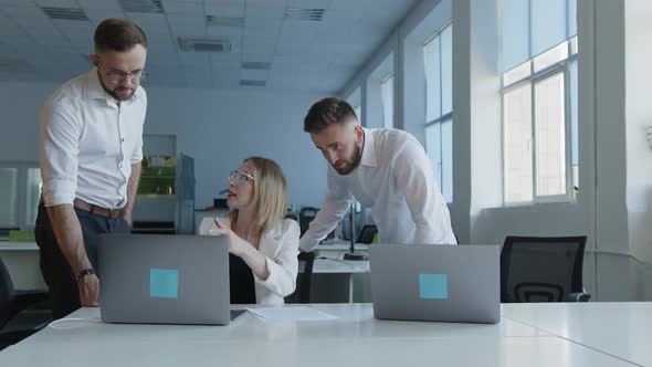 Girl Explains Online Work on Laptop to Her Colleagues