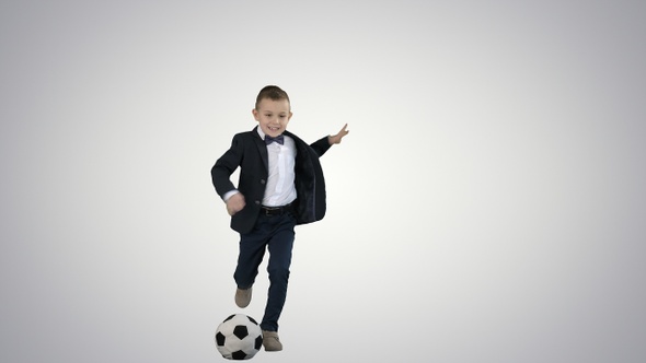 A cute boy in formal suit hitting a ball on gradient background.