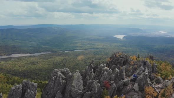 A Man Stands on a Rock Raising His Hands