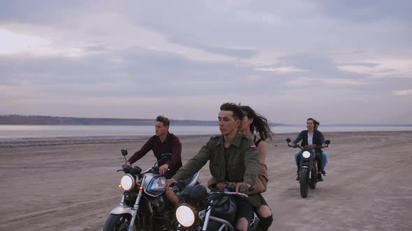 Group of Young People Riding Motorbikes on the Beach in Evening