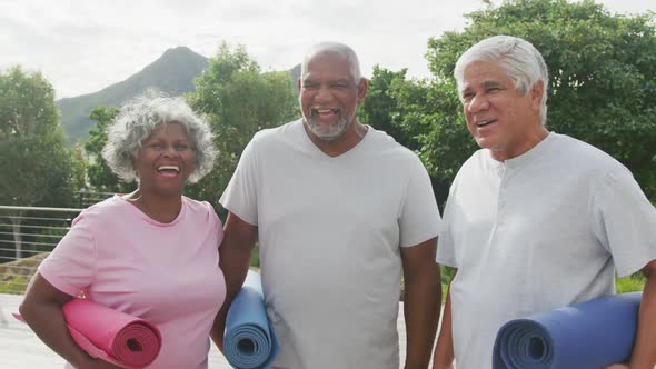 Portrait of happy senior diverse people practicing yoga in garden at retirement home