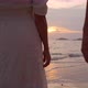 Young woman traveler holding man's hand and looking beautiful sunset on the beach - VideoHive Item for Sale