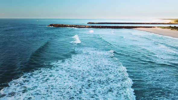 Drone moving sideways following waves as they break near beach. Ballina, Australia.