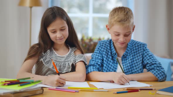 Portrait of Brother and Sister Drawing with Colorful Pencils at Home