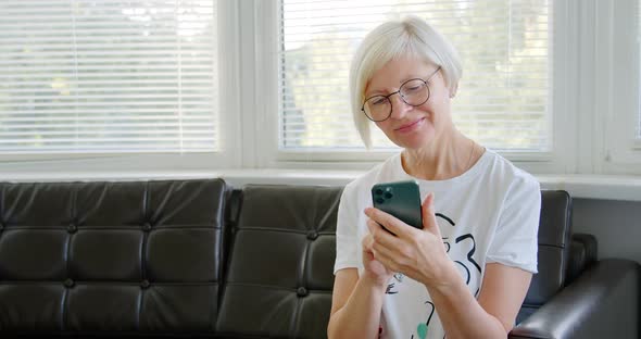 Mature woman using phone. Middle aged woman holding smart phone looking at cellphone screen