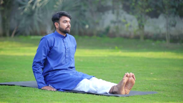 Indian man doing Dandasana or Staff Yoga Pose in an Indian traditional outfit Kurta Pajama