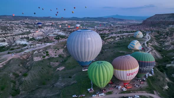 Hot air balloons fly over the mountainous landscape of Cappadocia, Turkey.