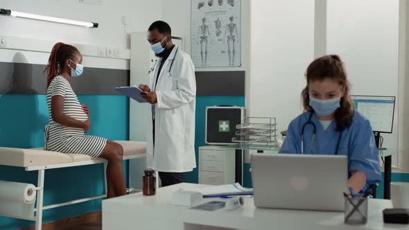 Pregnant Woman and Physician with Face Mask Doing Consultation