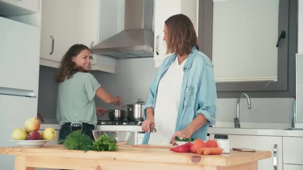 Two Young Pretty Caucasian Women Cooking in the Bright Kitchen.