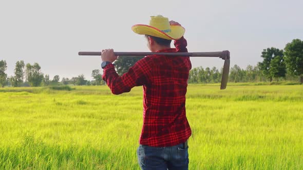 A farmer holding a hoe is walking