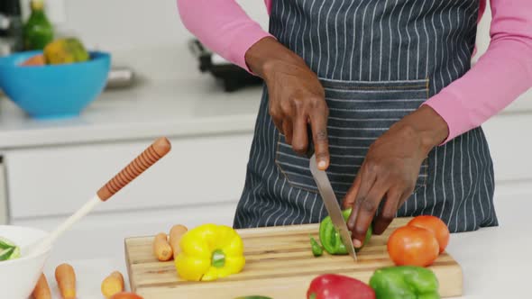 Happy woman cutting vegetables in kitchen