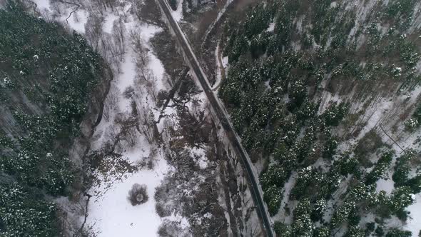 Aerial view of Cars driving on winter country road in snowy forest