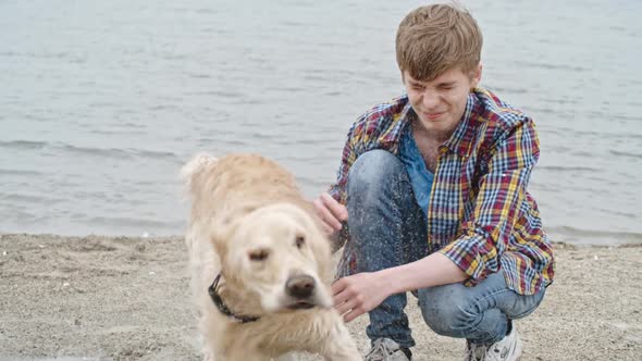 Teenage Boy Sitting with Labrador Dog Shaking Water All Over Him