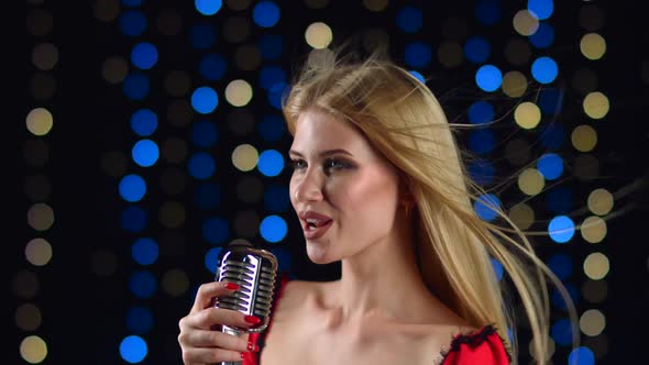 Girl Sings Energetic Songs in the Background Colored Lights. Side View