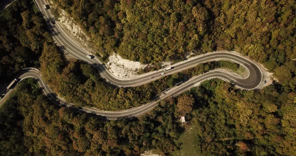 Aerial View of Car Driving Along The Winding Mountain Pass Road Through The Forest Trees. Autumn