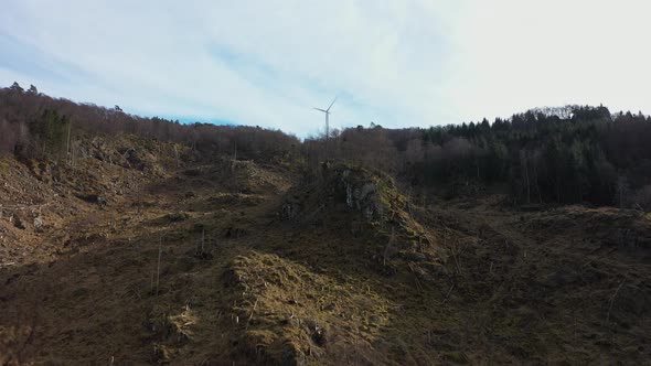 Flying up hillside against rotating wind turbine in Midtfjellet wind park - One single turbine produ