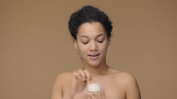 Beauty Portrait of Young African American Woman Who Take Face Cream Her Finger