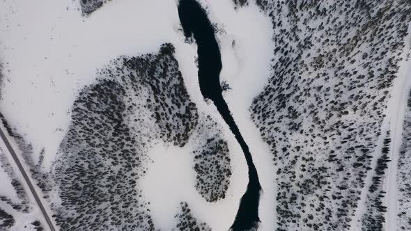 Aerial view looking down moving down over cold winter woodland lake in Norbotten Swedish landscape