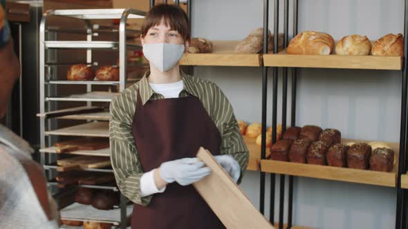 Woman in Mask and Gloves Selling Bread in Bakery
