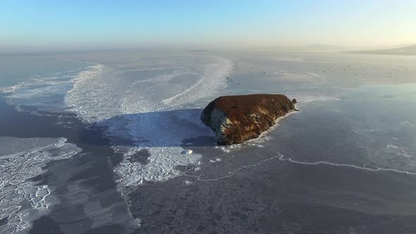 Drone View of a Rocky Island Among the Ice-covered Winter Sea