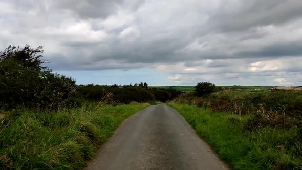 Narrow country road between villages in England, UK. Lots of green grass right next to the side of t