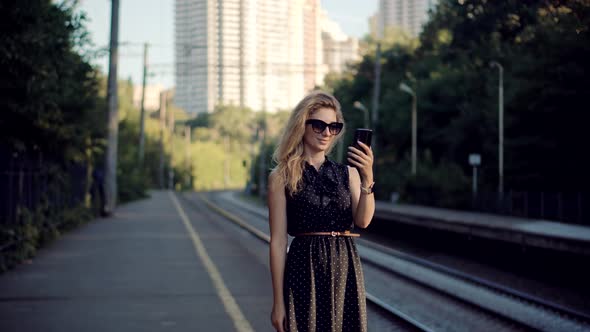 Woman Using Mobile Phone And Waiting Public Transport On Train Station. Active Lifestyle On Vacation