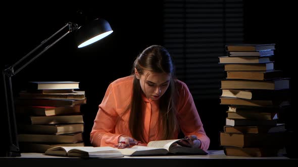 Girl Reads and Writes Information in a Notebook. Black Background