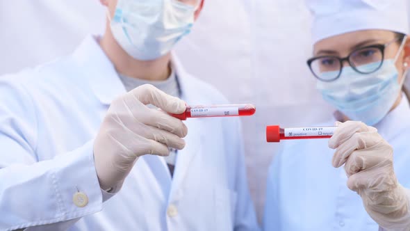 Male and Female Doctors Holds Test Tube with Blood Sample to Coronavirus