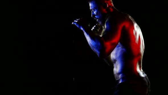 a Muscular Man with a Bare Torso and Golden Metallic Skin Fights with a Shadow Under Water Drops on