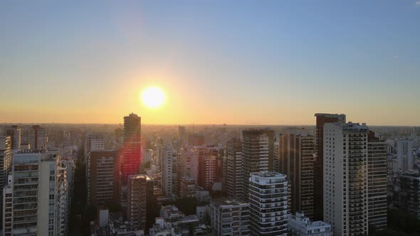 Dolly in flying between buildings and skyscrapers at sunset with bright sun setting in horizon, Buen