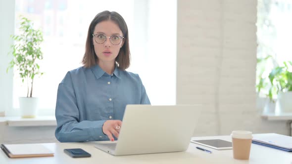 Young Woman Working on Laptop and Feeling Shocked in Modern Office