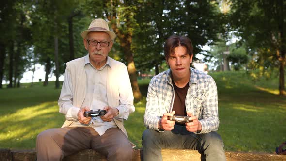 Grandson and Grandfather Hold Joystick and Play Exciting Games