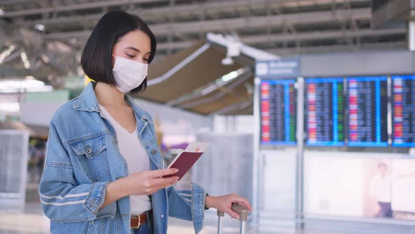 Woman passenger wearing face mask walking in airport terminal to boarding gate during Covid pandemic