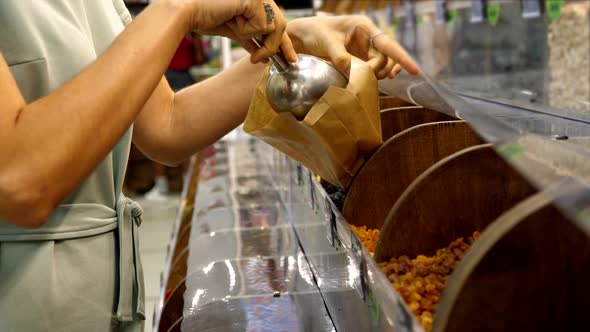 Young Caucasian Woman is Taking Raisins at Grocery Store