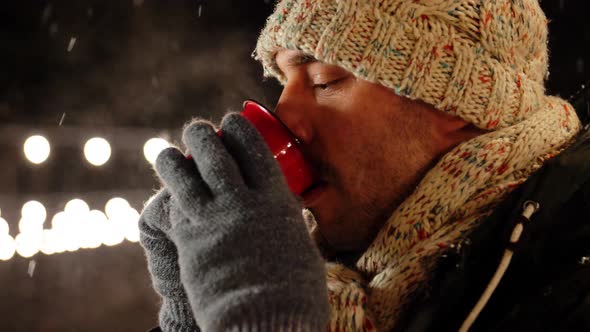 Happy Young Man Drinking Tea Outdoors in Winter