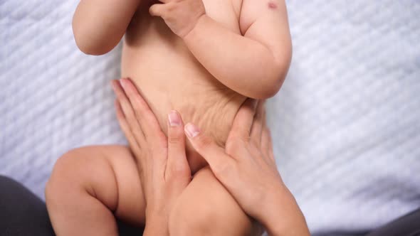 Female Hands Massage the Tummy of a Baby in a Diaper