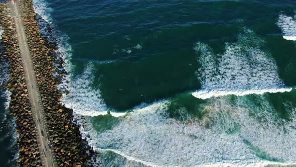 Looking down over Gold Coast seawall with waves crashing in at sunset