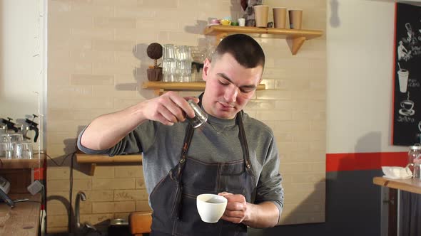 Man Barista Poured Into a Cup of Coffee Cinnamon in a Modern Coffee Shop.