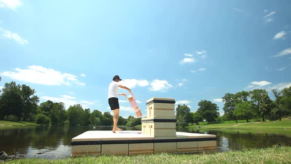 Father playing with daughter on floating platform on lake in France